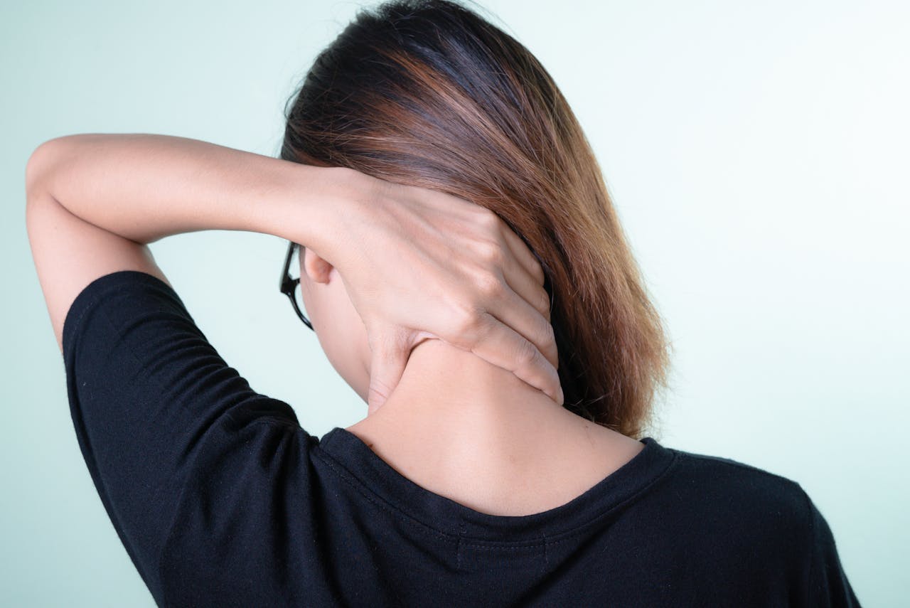 services-03 Rear view of a woman massaging her neck, depicting neck pain relief or self-care concepts.
